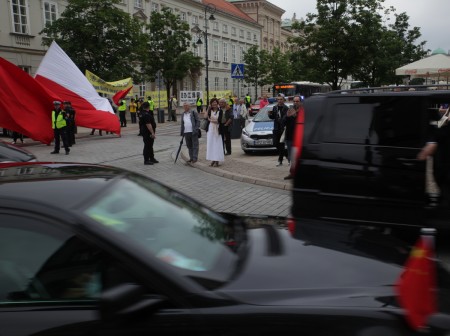 总统府外，习近平车队过来时，江派马仔煽动华人用波兰国旗遮挡法轮功条幅。（黄诃欧/大纪元）
